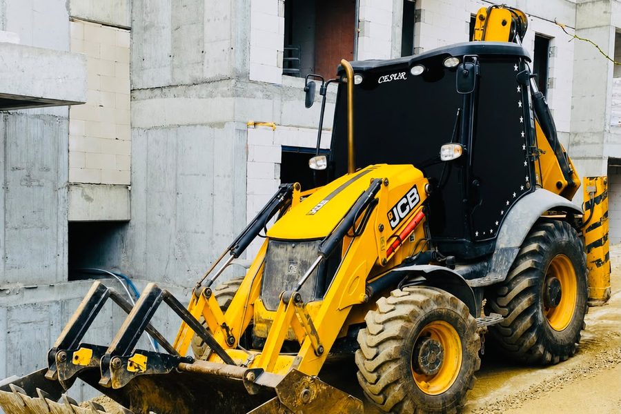 Kaba inşaat halindeki binanın önünde bekleyen sarı JCB beko loder kepçe