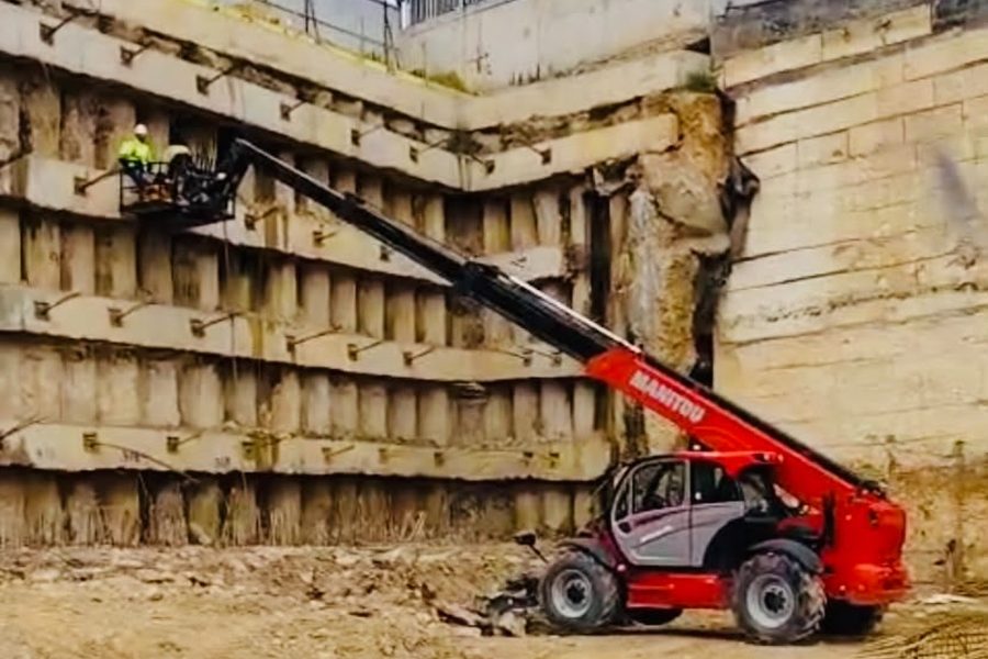 Manitou'nun personel sepetiyle iksa perde duvarında çalışan işçi